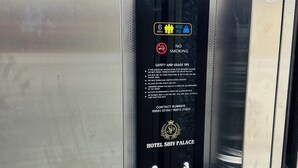 Panel de control de ascensor con pantalla digital, teclado y normas de seguridad.