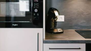 Eine Küche mit Mikrowelle, Kaffeemaschine und weißen Schränken.