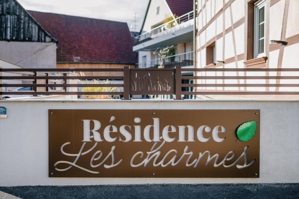 A sign for "Résidence Les Charmes" with a leaf symbol.
