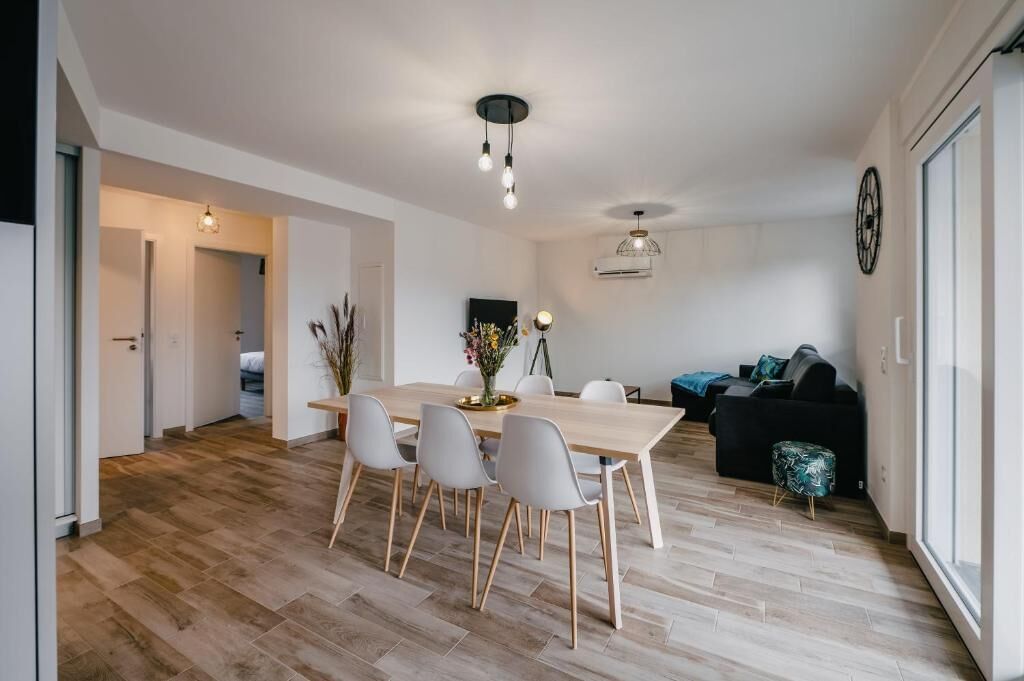 Ein stilvoller Wohnraum mit Essbereich, einer Couch und einem Fernseher.