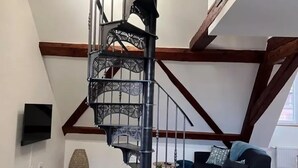 Modernilla designilla varustettu kierreportaikko, puupalkit ja seinälle asennettu litteänäyttöinen televisio.
