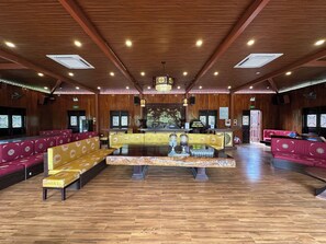 A spacious lobby with wooden paneling, a central reception desk, and seating areas. - La Vela Legacy Resort (Hue)