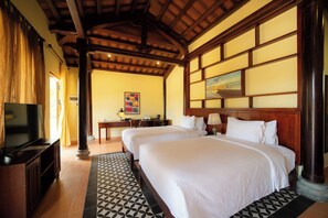 A hotel room with two beds, a desk, a television, and a painting on the wall.