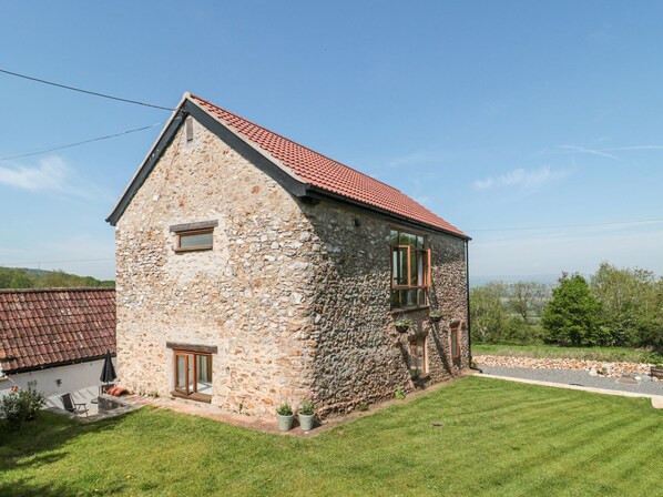 A stone house with a red-tiled roof, a small porch, and a grassy yard. - Newlands Barn (Wellington)
