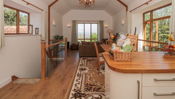 A spacious living area with a wooden staircase, a chandelier, and a view of the outdoors. - Newlands Barn (Wellington)
