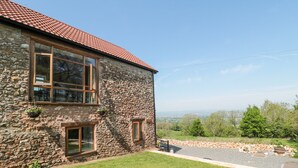 A stone house with a red-tiled roof, large windows, and a well-maintained lawn. - Newlands Barn (Wellington)