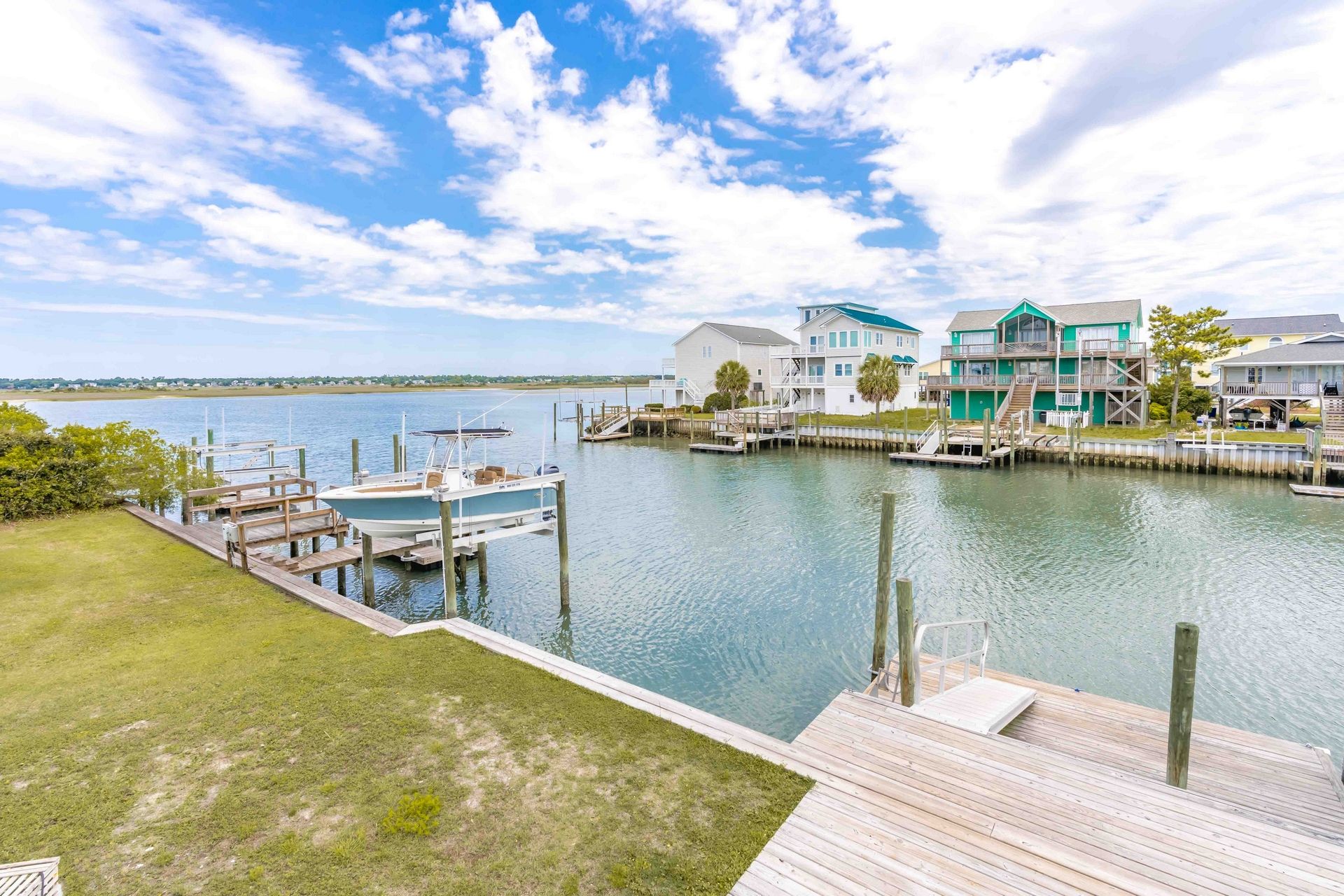 A waterfront property with a dock, a boat, and a house with a green roof.