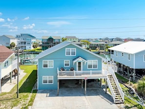 A two-story house with a front porch and a dock extending into the water.