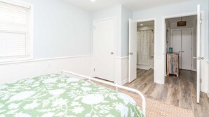 Une chambre à coucher avec un lit, une porte donnant sur une salle de bain et un petit placard.