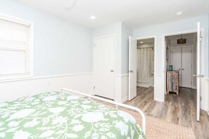 A bedroom with a bed, a door leading to a bathroom, and a small cabinet.