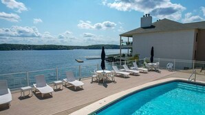 Zona de piscina con sillones de descanso y vista a un lago.