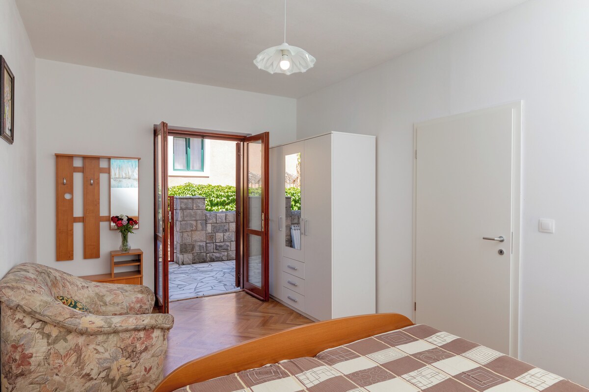 Un dormitorio con cama, armario, silla y puerta que da a un espacio exterior.