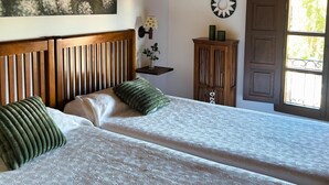 A bedroom with two beds, wooden headboard, a painting, a clock, and a window with a view. - 2 bedroom apartment in the historic center of Isla, close to the beach. (Isla)