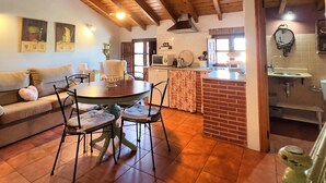 A cozy living room with a wooden ceiling, a dining table with chairs, a sofa, and a kitchen area with a sink and a microwave. - 2 bedroom apartment in the historic center of Isla, close to the beach. (Isla)