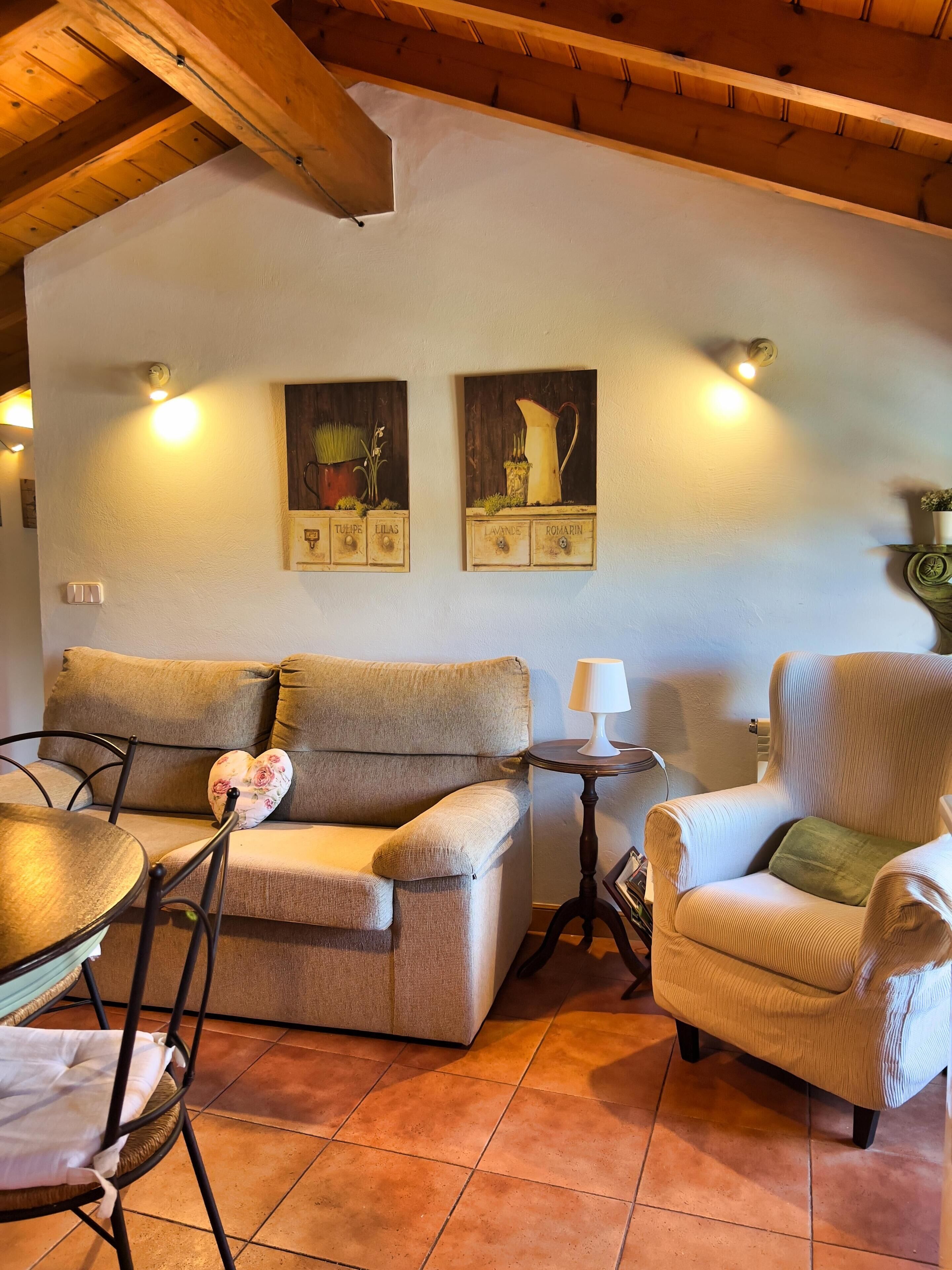 Una sala de estar acogedora con un sofá, sillones, una mesita y obras de arte colgadas en la pared.