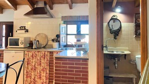 A kitchen with wooden beams, a microwave, a sink, and a dining area with a chair. - 2 bedroom apartment in the historic center of Isla, close to the beach. (Isla)