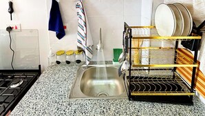 Een keuken met granieten aanrechtbladen, een roestvrijstalen spoelbak, houten keukenkastjes en een afwasschaal.