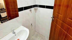 Een badkamer met een douche, wastafel en spiegel.