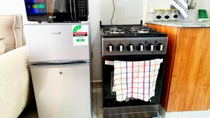 Een kleine keuken met een koelkast, magnetron, fornuis en oven.