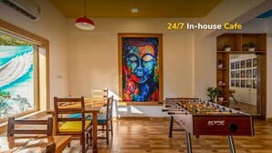 Ein Café mit rund um die Uhr geöffnetem Service, Holzkuben, einem Tischfußballspiel und einem Buddha-Gemälde.