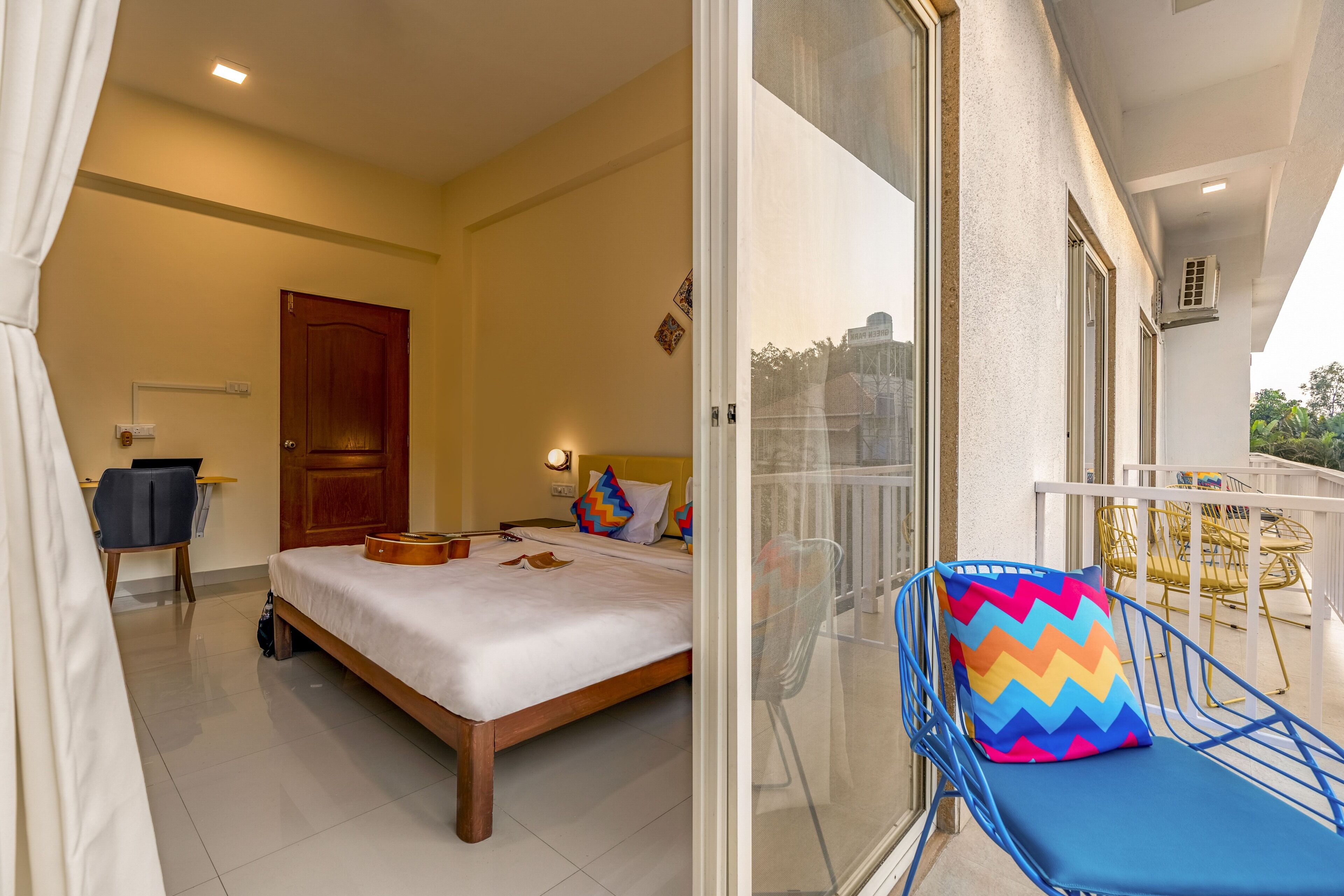 Une chambre d’hôtel avec un lit, un bureau et un balcon équipé de chaises.