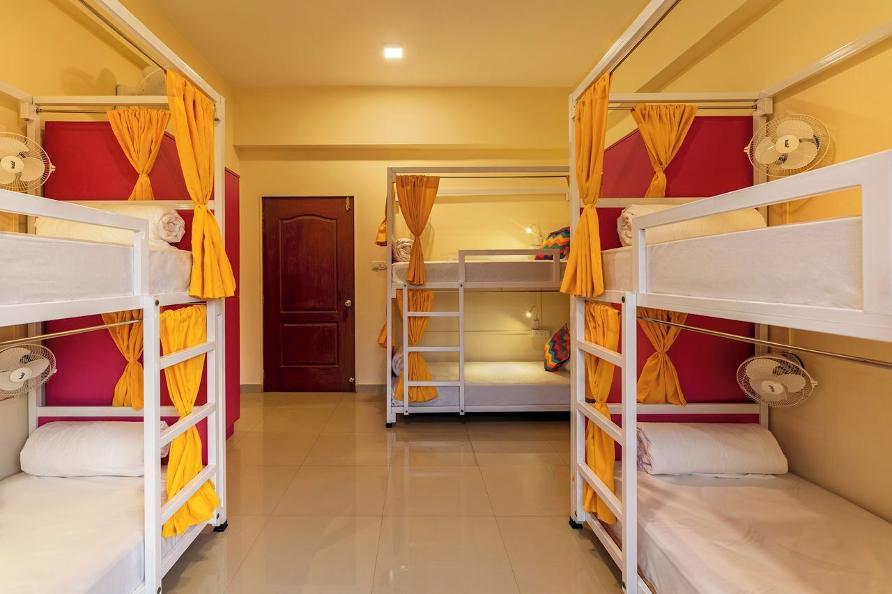 Una habitación de hotel con literas, cada una con un ventilador y cortinas amarillas.