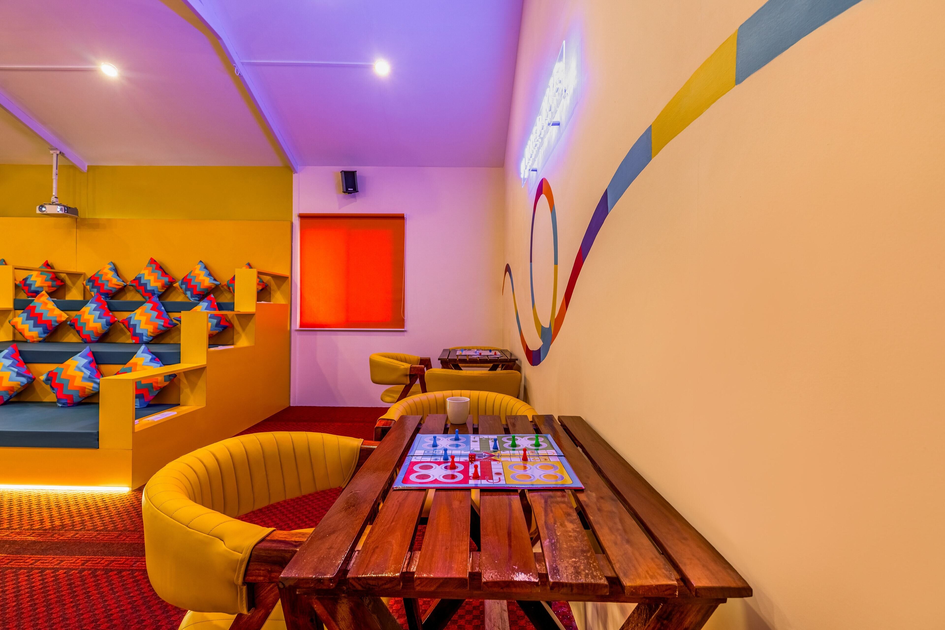 Una habitación con una mesa de madera, sillas amarillas, un cuadro de pared colorido y una pared de acento roja.