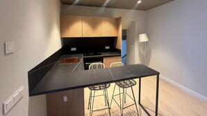 Una cucina compatta con isola centrale, sgabelli da bar e un design moderno.