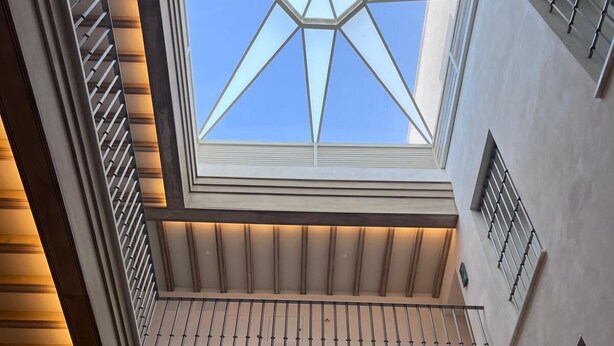 Un lucernario con un motivo geometrico, una ringhiera in legno e uno stile architettonico moderno.