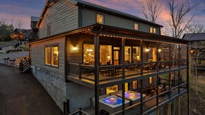 A two-story building with a covered patio area, outdoor seating, and hot tubs.