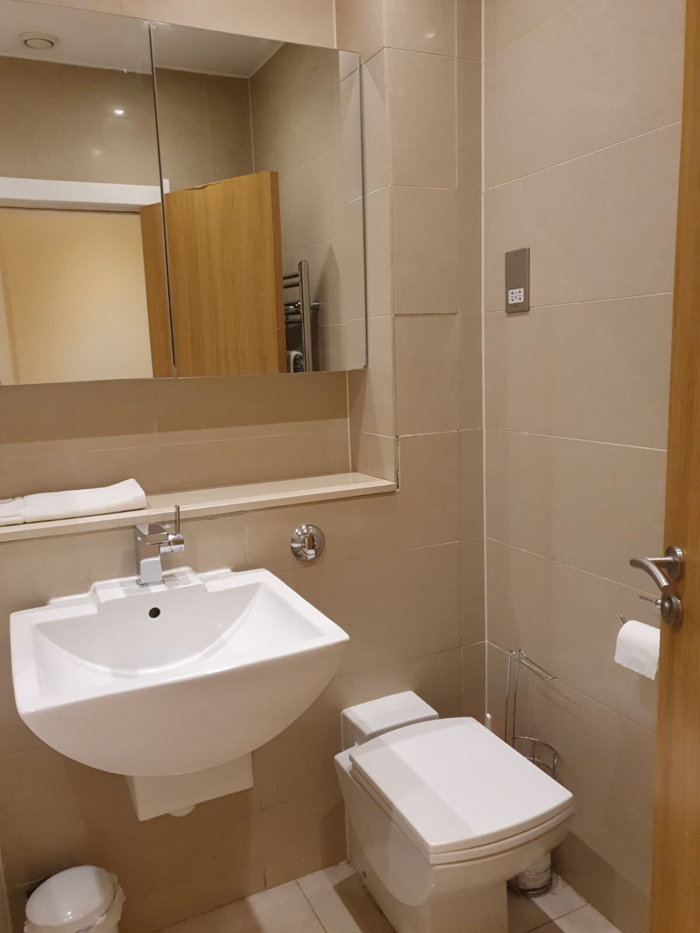 Ein modernes Badezimmer mit Waschbecken, Spiegel und Toilette in Weiß.