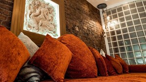A room with a brick wall, a framed artwork, and a row of orange cushions. - Infinity Partypadsliverpool Hen and Stag Welcome (Liverpool)