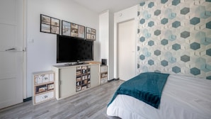 A bedroom with a bed, a TV, a dresser, and a wall with geometric patterns. - 300m from the sea - garden and small pool (Pornic)