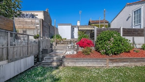 A residential area with a wooden fence, a small garden with red flowers, and a clear blue sky. - 300m from the sea - garden and small pool (Pornic)