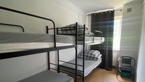 Ein Schlafsaalzimmer mit Etagenbetten, einem Stuhl und einem Heizkörper.