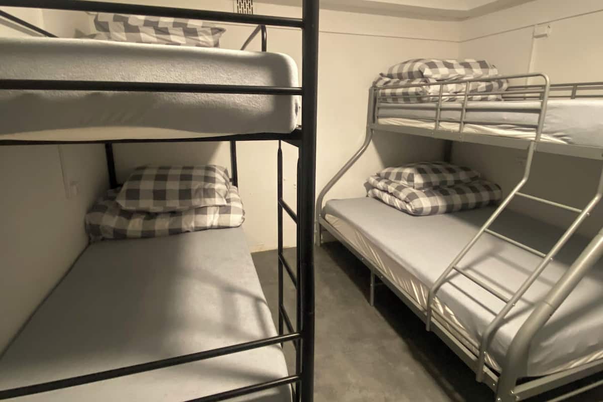 A bunk bed room with two bunk beds, each with a mattress and checkered pillow.