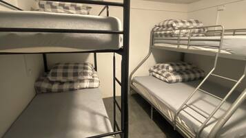 A bunk bed room with two bunk beds, each with a mattress and checkered pillow.
