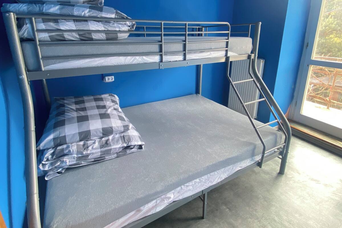 A bunk bed room with blue walls and a window.