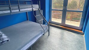 Ein Schlafsaalzimmer mit Etagenbetten, einem großen Fenster und Blick ins Freie.