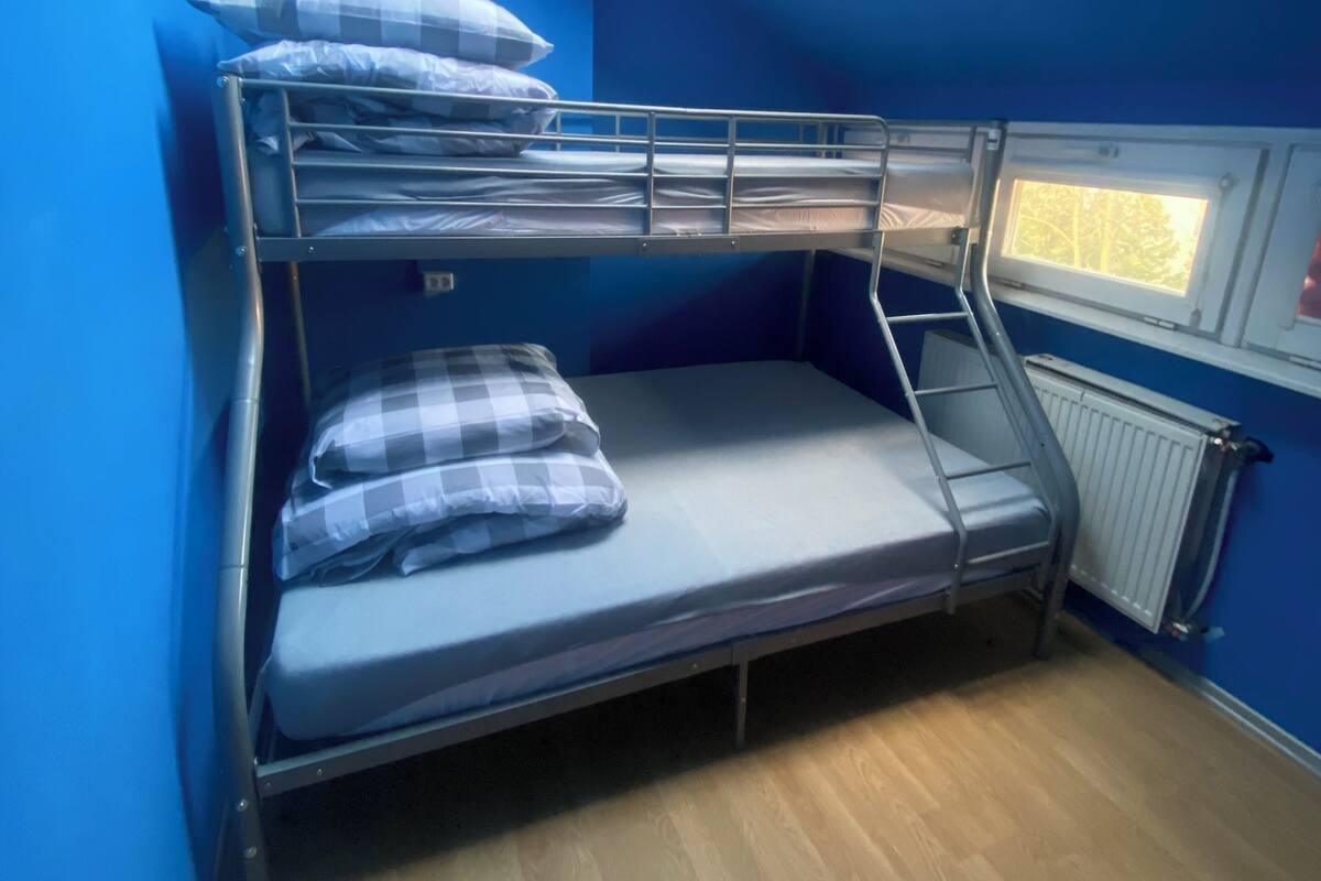 A bunk bed room with a skylight, a window, and a radiator.