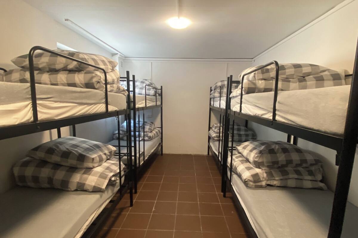 A narrow room with four bunk beds arranged in a row, each with checkered bedding.