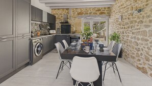 Una cocina moderna con armarios grises, una lavadora y un comedor con mesa y sillas.