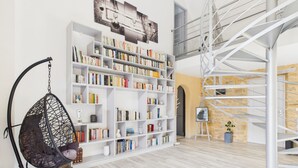 Una habitación amplia con una gran estantería blanca, un sillón colgante y una escalera de caracol.