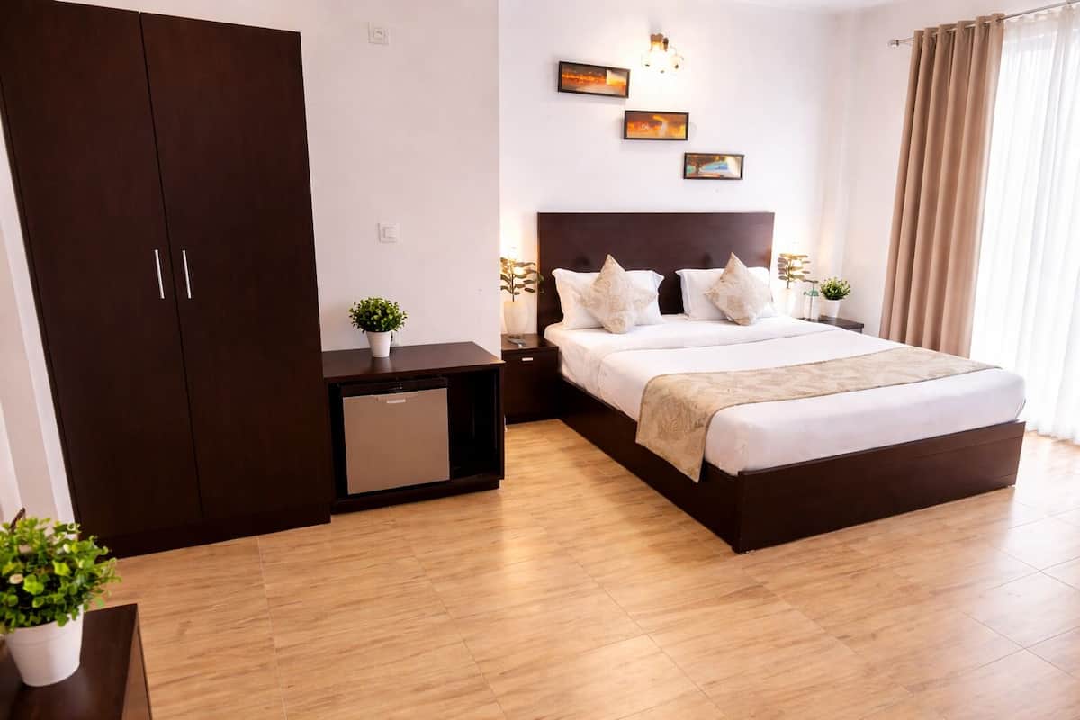 Habitació d'hotel amb llit, taula de nit, làmpada i armari.