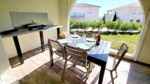An outdoor dining area with a table set for four, a grill, and a view of a residential area. - T2 renovated chic - terrace & sea view (Linguizzetta)