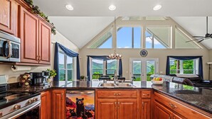 A kitchen with wooden cabinets, a microwave, a stove, and a sink. - View-Tastic in The Valley / Hot Tub / Views (Maggie Valley)