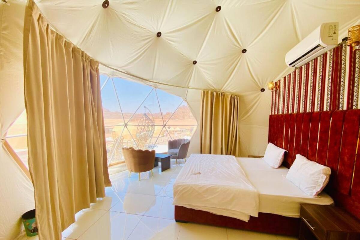 A room with a bed, a chair, and a view of the outdoors.