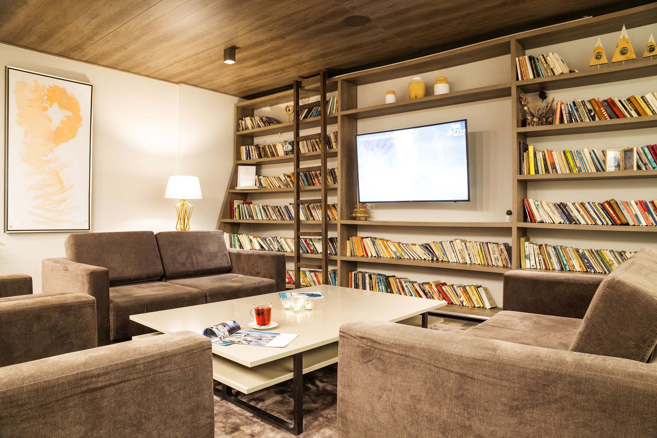 Una sala lettura accogliente con un divano, poltrone, un tavolino da caffè e scaffali colmi di libri.