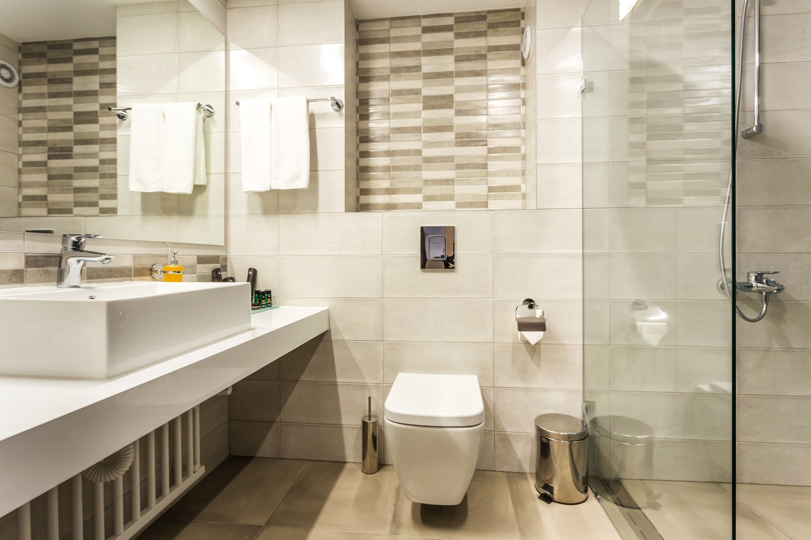 A modern bathroom with a large sink, toilet, and glass shower enclosure.