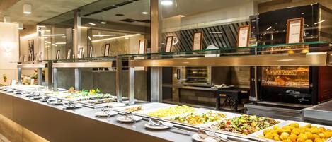 A buffet with various food options, a glass display case, and a kitchen area in the background.